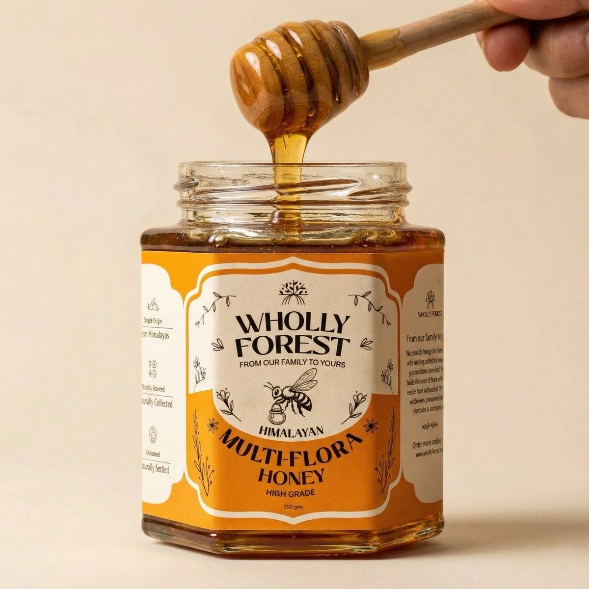 Raw honey flowing from a wooden dipper beside a Wholly Forest jar